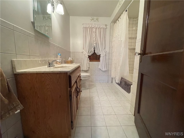 bathroom with vanity, toilet, curtained shower, tile walls, and tile patterned flooring