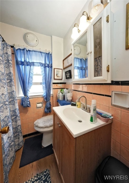 bathroom with vanity, toilet, tile walls, and hardwood / wood-style flooring