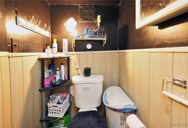 bathroom with toilet and wood walls