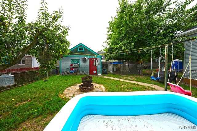 view of pool featuring an outdoor fire pit, a playground, a yard, and a trampoline