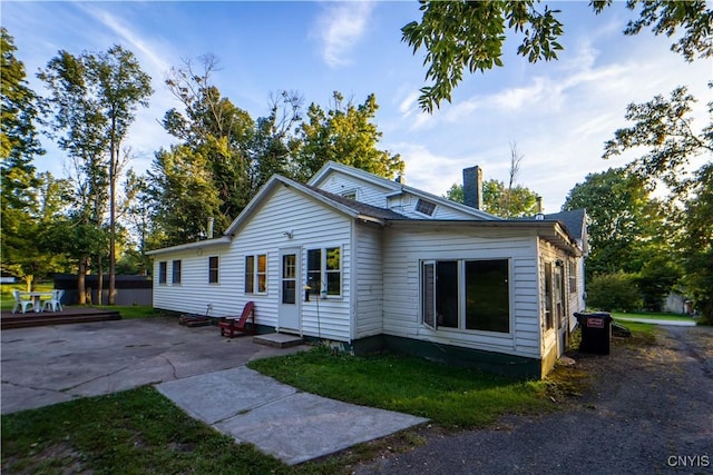 view of front of house with a patio area, entry steps, and a chimney