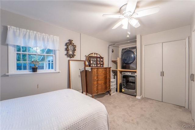 bedroom featuring a closet, light colored carpet, stacked washer and clothes dryer, and a ceiling fan