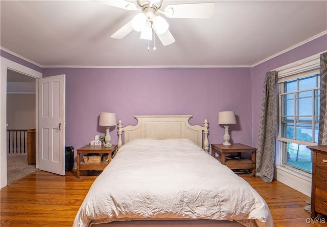 bedroom with multiple windows, crown molding, a ceiling fan, and wood finished floors