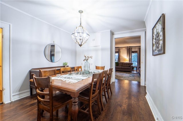 dining area featuring dark wood-type flooring, ornamental molding, and a chandelier
