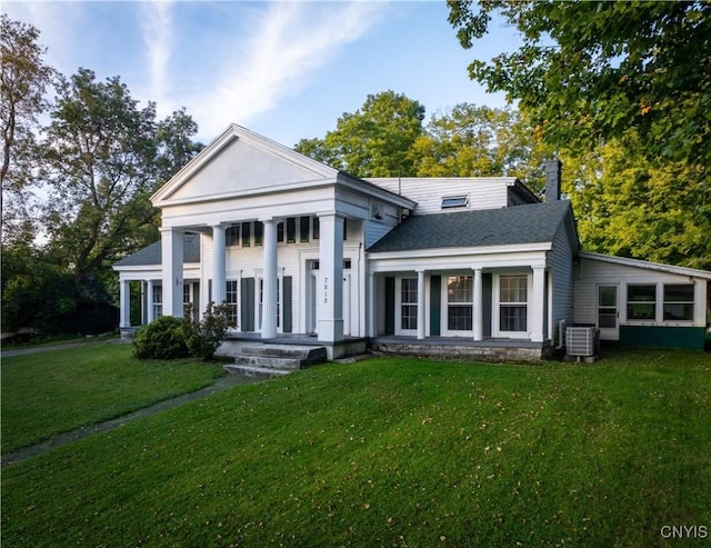 greek revival house with a front yard, central air condition unit, covered porch, and a shingled roof