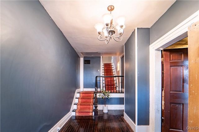corridor with stairway, visible vents, baseboards, wood-type flooring, and a chandelier