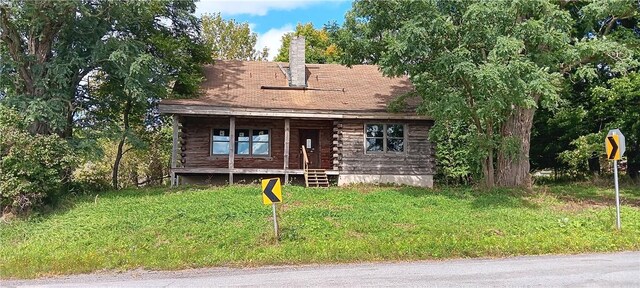 log-style house featuring a front lawn and a porch