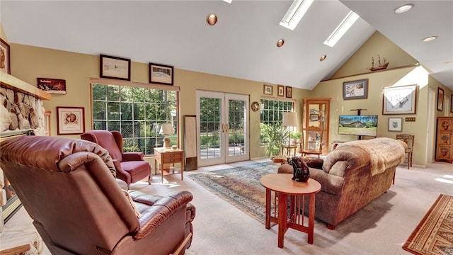 carpeted living room with high vaulted ceiling, a skylight, french doors, and a stone fireplace