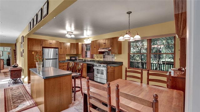 kitchen featuring black appliances, a center island, decorative light fixtures, sink, and a notable chandelier