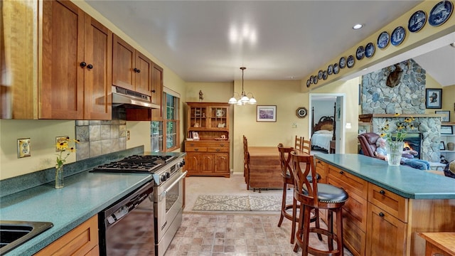 kitchen featuring decorative light fixtures, stainless steel appliances, an inviting chandelier, a fireplace, and decorative backsplash