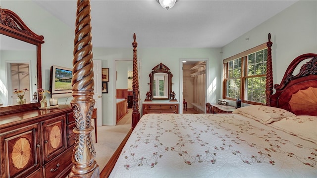 carpeted bedroom featuring a spacious closet, ensuite bathroom, and a closet