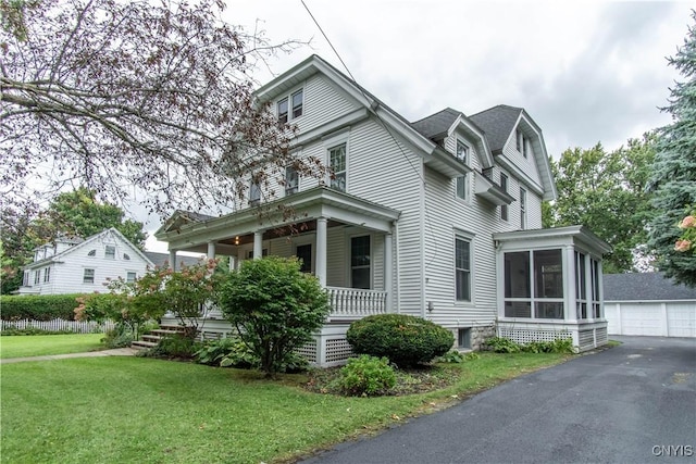 view of front of house with a front lawn, a gambrel roof, a porch, a sunroom, and an outbuilding