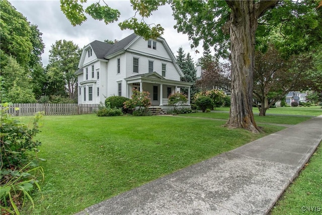 view of front of house featuring covered porch, a gambrel roof, a front lawn, and fence