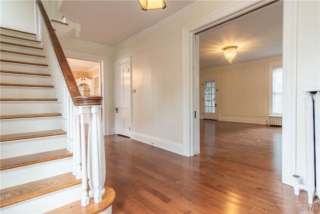 staircase featuring crown molding, radiator heating unit, baseboards, and wood finished floors