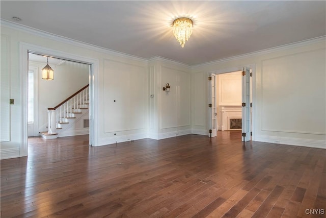 unfurnished room featuring dark wood finished floors, stairway, a decorative wall, and crown molding