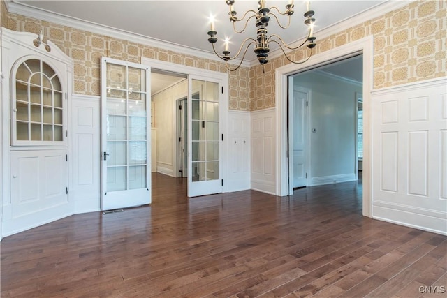 empty room with dark wood-type flooring, wainscoting, and wallpapered walls