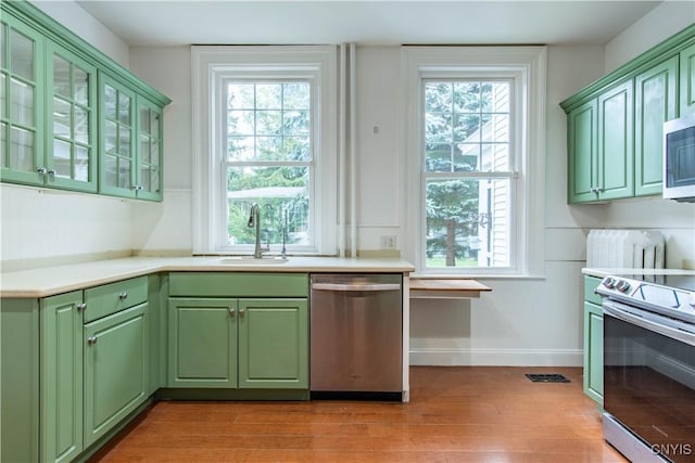 kitchen with plenty of natural light, stainless steel appliances, green cabinets, and a sink