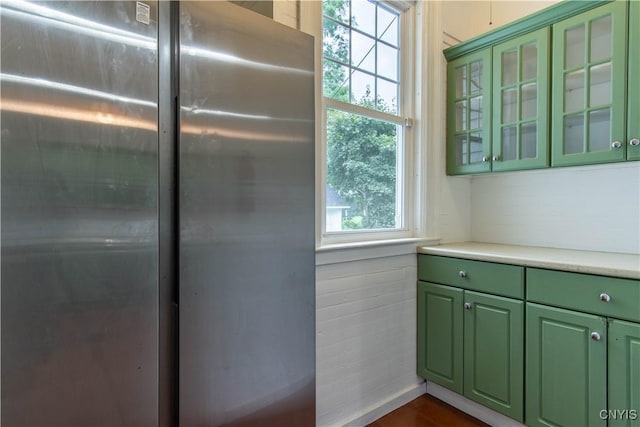 kitchen featuring dark wood-style floors, freestanding refrigerator, green cabinets, light countertops, and glass insert cabinets