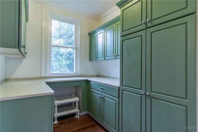 kitchen with crown molding, green cabinets, dark wood-type flooring, light countertops, and built in desk