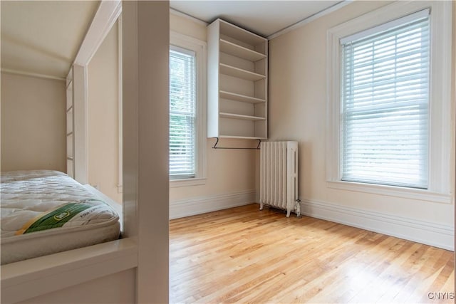 bedroom with light wood-style floors, baseboards, and radiator