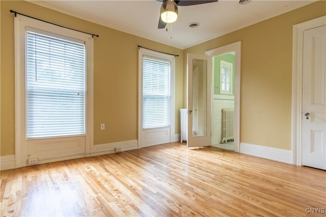 unfurnished room featuring visible vents, radiator, baseboards, wood finished floors, and a ceiling fan