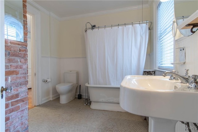 full bath with toilet, a washtub, a shower with shower curtain, wainscoting, and crown molding