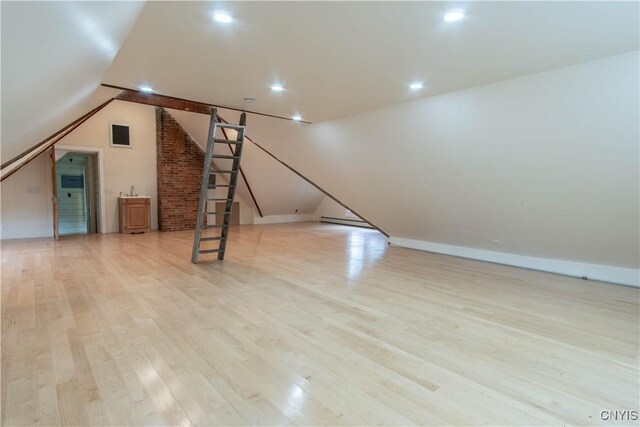 additional living space with stairway, baseboards, recessed lighting, vaulted ceiling, and light wood-type flooring