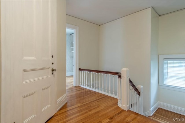 hallway featuring light wood-style flooring, an upstairs landing, and baseboards