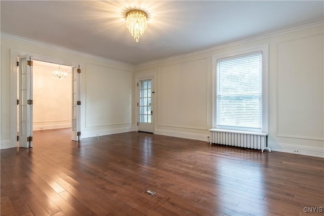 unfurnished room featuring dark wood-type flooring, a decorative wall, radiator heating unit, and a chandelier