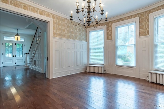 unfurnished dining area with a wainscoted wall, radiator, radiator heating unit, and wallpapered walls