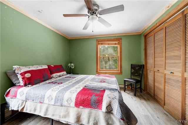 bedroom with crown molding, hardwood / wood-style floors, ceiling fan, and a closet