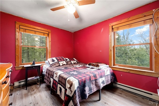 bedroom featuring light hardwood / wood-style flooring, a baseboard radiator, and ceiling fan