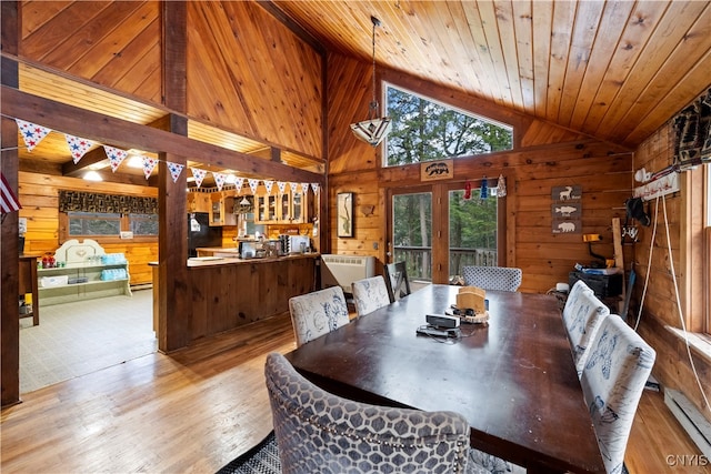 dining area featuring wooden walls, light hardwood / wood-style flooring, lofted ceiling with beams, baseboard heating, and wood ceiling