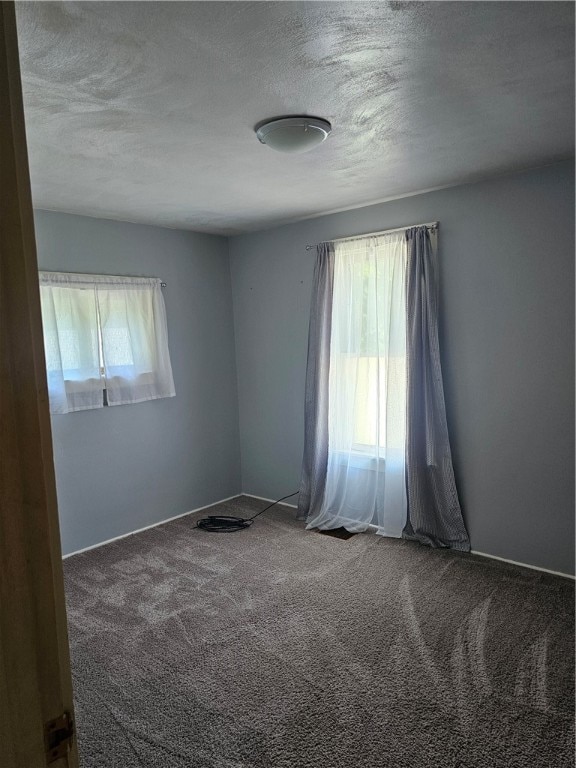 carpeted empty room with a textured ceiling