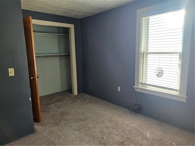 unfurnished bedroom with a closet, carpet, and a textured ceiling