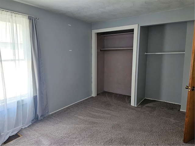 unfurnished bedroom featuring multiple windows, a textured ceiling, a closet, and carpet