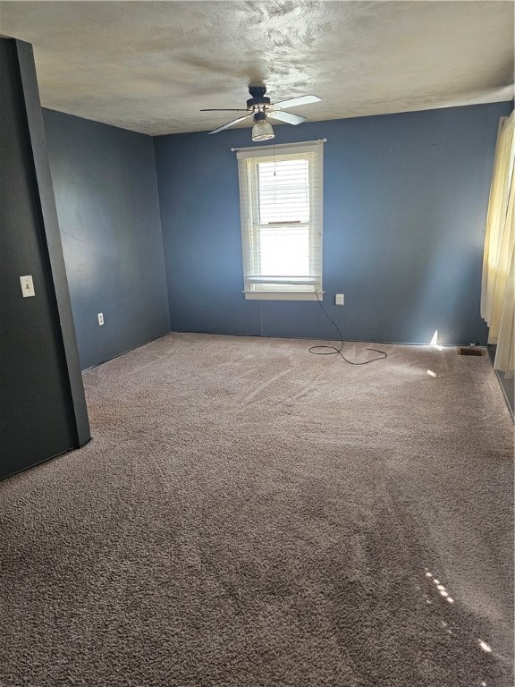 carpeted empty room featuring a textured ceiling and ceiling fan