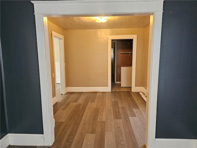 corridor with washer / clothes dryer and light hardwood / wood-style flooring