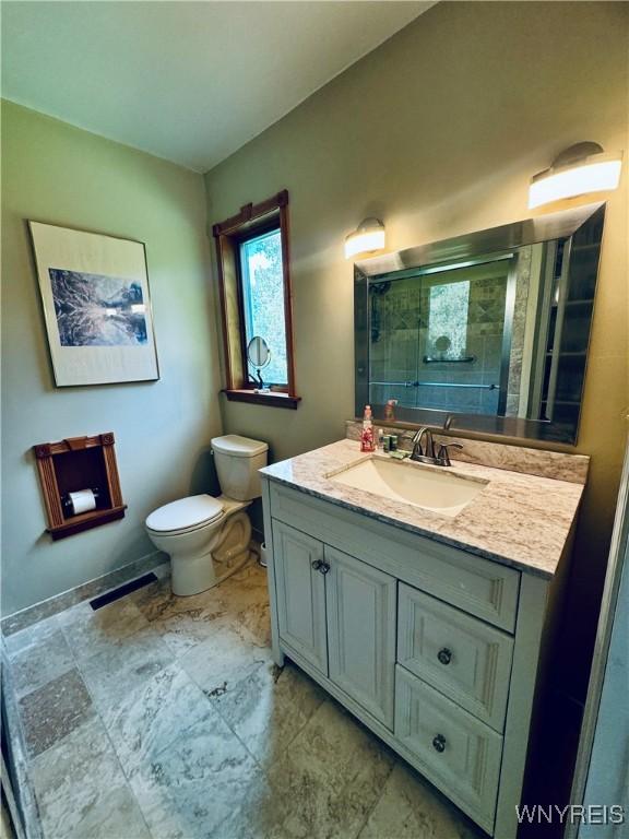 bathroom featuring walk in shower, vanity, and toilet