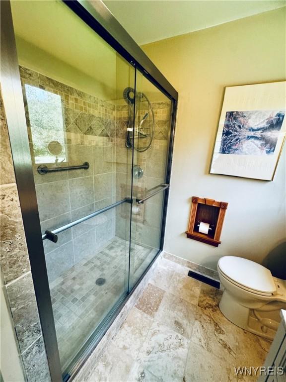 bathroom with a shower with door and toilet