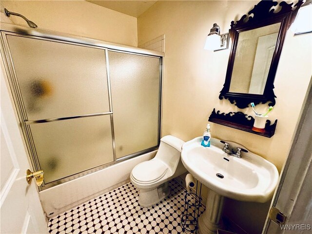 full bathroom with enclosed tub / shower combo, toilet, and sink