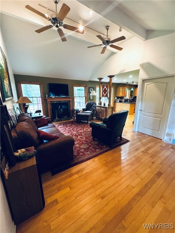 living room featuring light hardwood / wood-style floors, lofted ceiling with beams, and ceiling fan