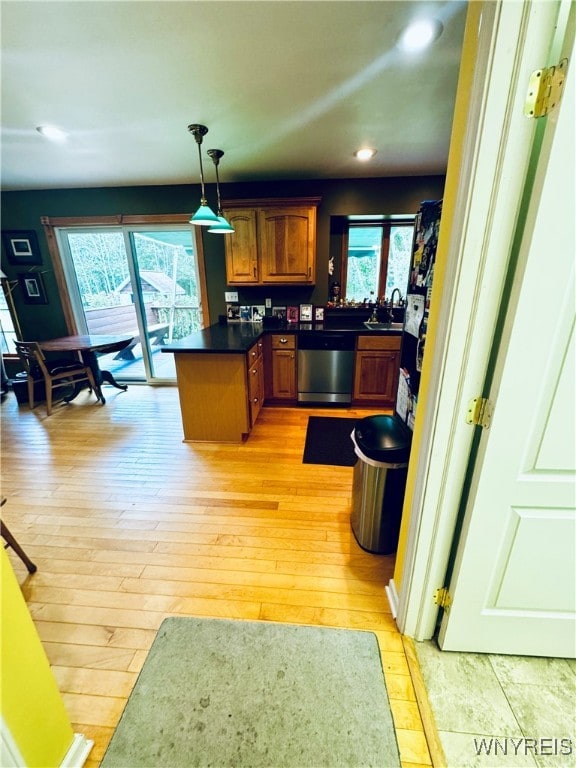 kitchen with hanging light fixtures, sink, kitchen peninsula, stainless steel dishwasher, and light wood-type flooring