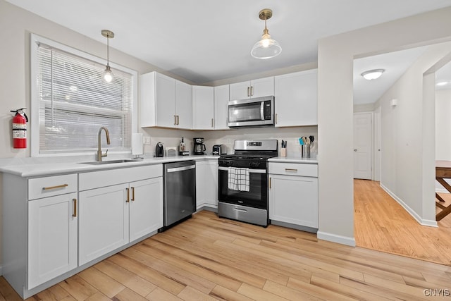 kitchen featuring light wood-type flooring, white cabinets, stainless steel appliances, and sink