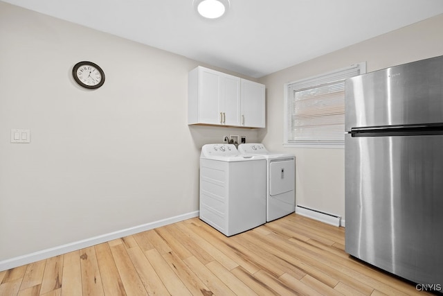 clothes washing area with light wood-type flooring, baseboard heating, washing machine and dryer, and cabinets