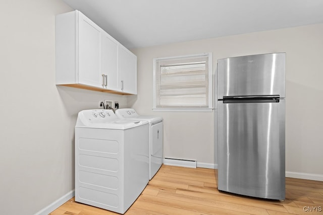 laundry room featuring a baseboard radiator, washing machine and clothes dryer, cabinets, and light hardwood / wood-style flooring