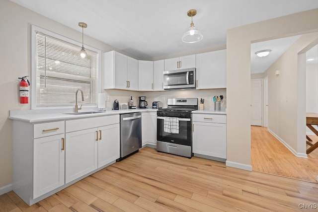 kitchen with appliances with stainless steel finishes, light hardwood / wood-style flooring, and pendant lighting