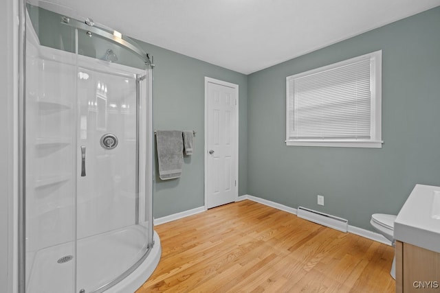 bathroom with toilet, an enclosed shower, vanity, a baseboard heating unit, and hardwood / wood-style flooring