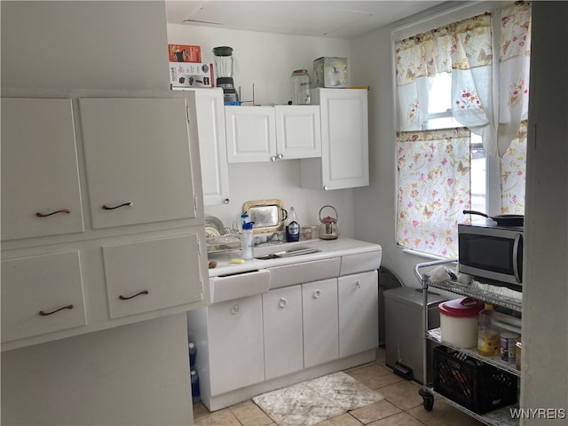 kitchen with white cabinetry, sink, and light tile patterned flooring