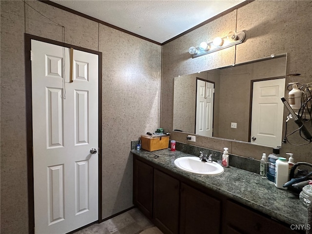 bathroom featuring ornamental molding, vanity, and a textured ceiling